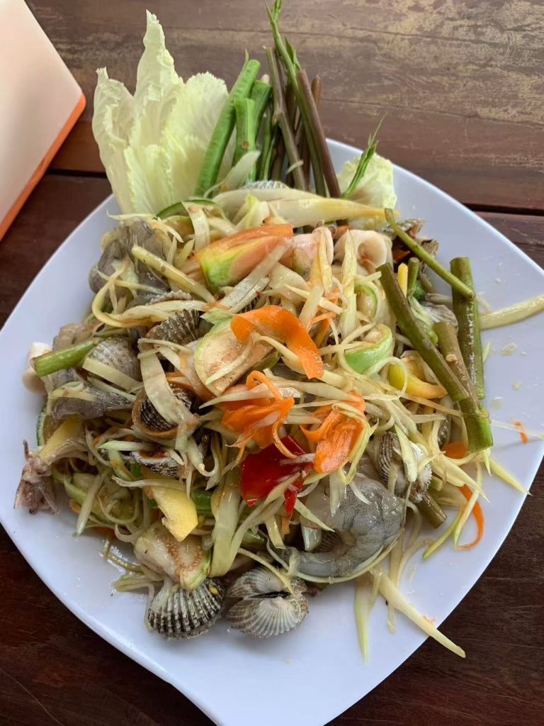 A plate of Cambodian green papaya salad with shrimp, shellfish, and vegetables — a refreshing and spicy street food favorite in Phnom Penh.