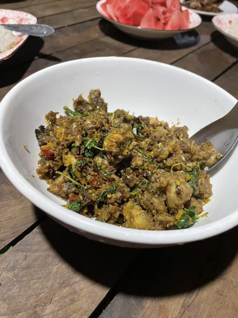 A traditional Cambodian stir-fried field mouse dish with herbs and spices, served in a white bowl.