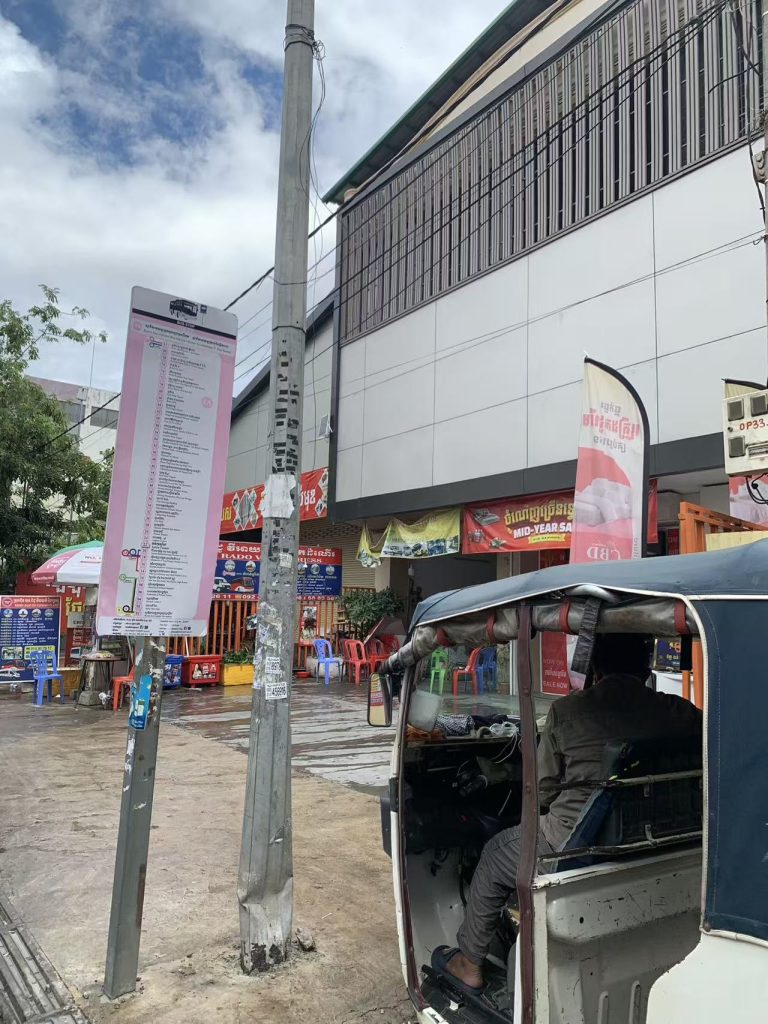 Street traffic in Phnom Penh with tuk-tuks, motorbikes, and cars during daytime.