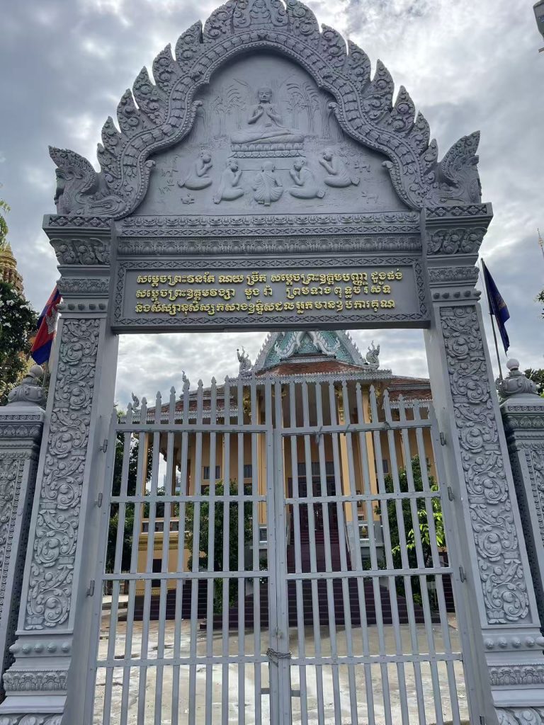 Entrance gate of Wat Ounalom Monastery in Phnom Penh featuring intricate Buddhist carvings.