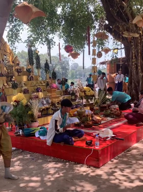 Cambodian New Year religious ceremony with offerings and monks near Angkor temple.