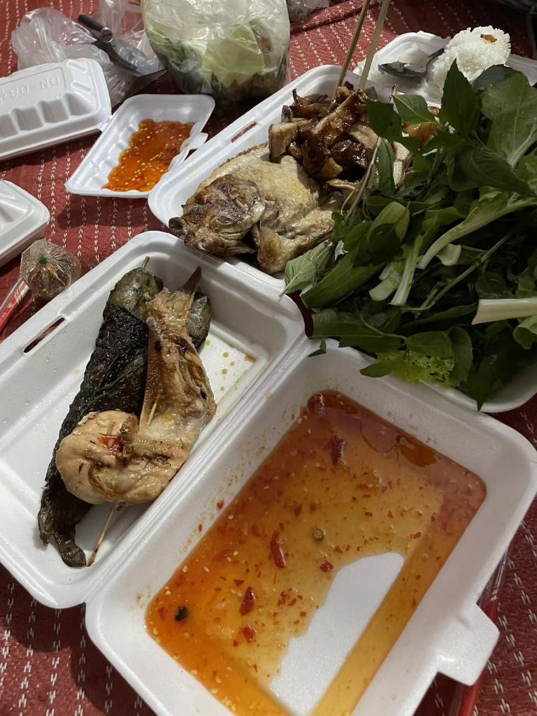 Traditional Cambodian New Year meal with grilled fish, herbs, and spicy dipping sauce.