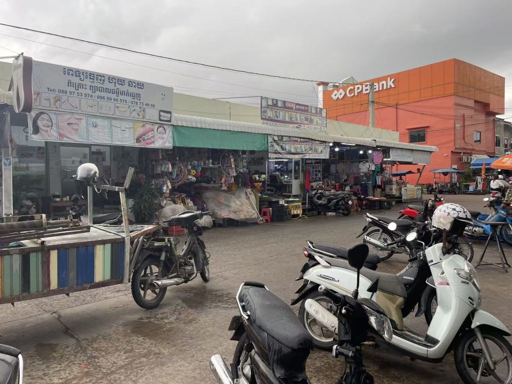 Street view of Cambodian local shops and clothing stores with motorcycles parked outside
